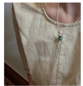 Detail of silver snake chain necklace with turquoise stone and black bead pendant