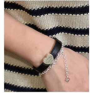 Close-up of S925 sterling silver heart charm with engraving on black leather strap