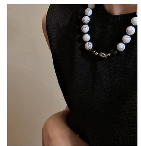 Close-up of marble and black beads necklace with embossed silver metal piece