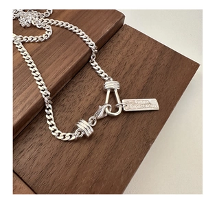 Detailed macro shot of silver curb chain with rectangular Future Expectation tag