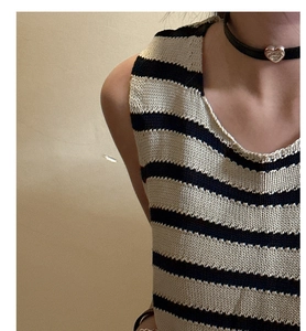 Detail view of heart pendant necklace with black leather cord and striped knit vest