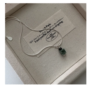 Macro detail of S925 sterling silver necklace with green stone pendant on snake chain