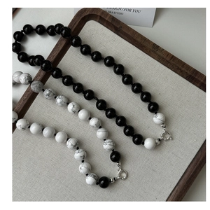 Detail of S925 silver necklaces with black beads and white marble stones on a tray