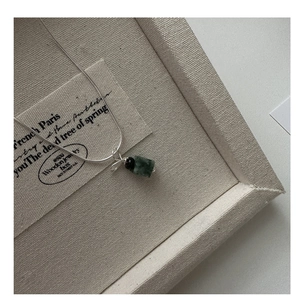 Close-up of a vintage silver snake chain necklace with a green jade pendant and black bead