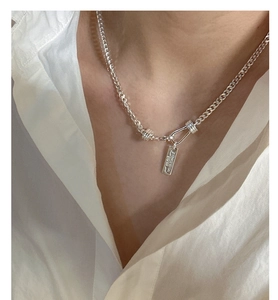 Detail of S925 silver flat chain necklace with engraved Expectation tag on white shirt