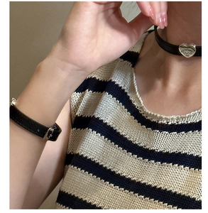 Close-up of black leather heart choker and bracelet set with silver metal engravings