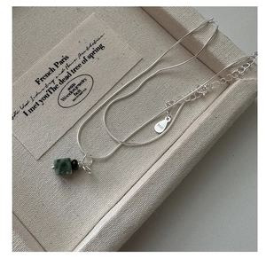 Macro shot of S925 sterling silver snake chain with dark green cubic gemstone pendant
