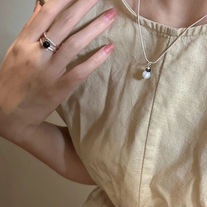 Élégant collier en perles argent S925 et bague assortie sur un mannequin en lin beige