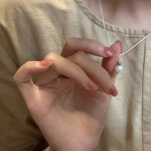 Collier minimaliste en argent S925 avec pendentif perle porté sur une chemise en lin