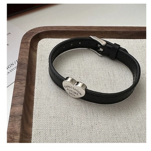 Close-up of S925 silver heart charm on black leather strap with engraved expectation text