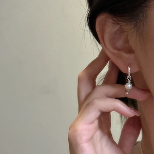 Boucles d'oreilles créoles S925 en argent sterling avec perle blanche portées par un mannequin