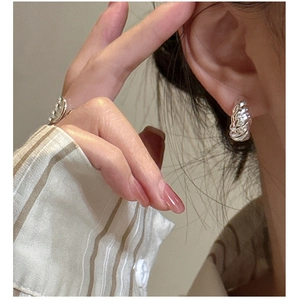 Macro detail of silver croissant twist texture on the earring and adjustable ring