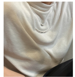 Detail of S925 sterling silver layered necklace with frosted smile bar on beige sweater