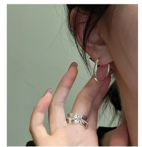 Close-up of minimalist S925 sterling silver C-shaped hoop earrings and wavy open ring