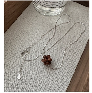 Macro detail of S925 sterling silver stamp and sparkling brown bead pendant on a fine chain