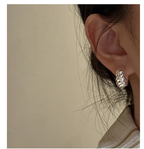 Close-up of S925 sterling silver croissant twist hoop earrings worn by a model