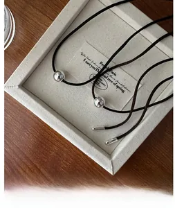 Detail view of S925 silver beads on a brown adjustable cord necklace over a tray