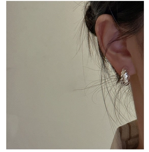 Detail of s925 silver croissant hoop earring with twisted rope texture on model