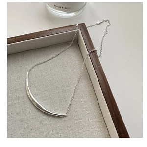 Detail of minimalist S925 sterling silver smile necklace on luxury display tray