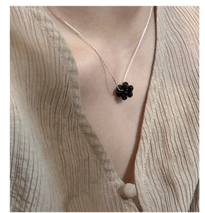 Close-up of s925 silver necklace with black beaded fruit pendant on a model shirt