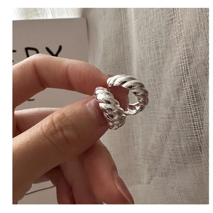 Macro view of twisted S925 silver croissant hoop earrings with polished metal texture