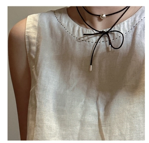 Detail of S925 silver bead choker on black cord tied as a bow with linen top