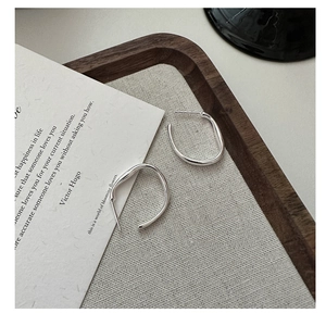 Macro detail of minimalist S925 sterling silver C-shaped earrings with a polished finish