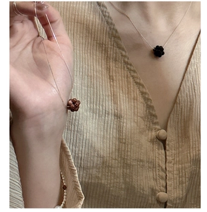Detail of handmade beaded spherical flower pendants on delicate silver and gold chains