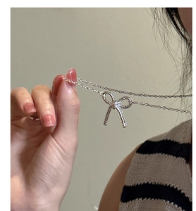 Close-up of S925 sterling silver bow pendant necklace with twist texture on model