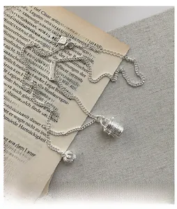Detail of S925 silver necklace with vintage bucket bag and crown charms on a book