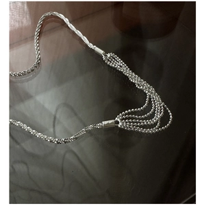 Detail of layered S925 sterling silver necklace featuring mixed chains and ball tassels