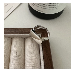 Macro detail of silver square geometric ring on wooden jewelry box with a smooth finish