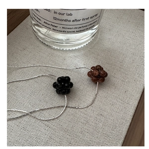 Detailed macro view of S925 silver necklace with black and brown beaded fruit pendants