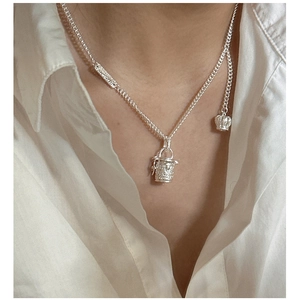 Detail of S925 silver necklace with woven barrel pendant and side crown charm on a model
