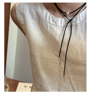 Detail showing minimalist double-layer black cord necklace with a silver bead on a model