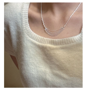 Detail of layered S925 sterling silver tassel chain necklace on a model's neck