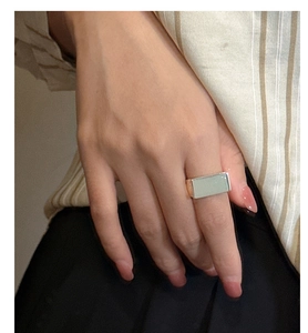 Detail of square silver ring with smooth green inlay on hand of a model in striped shirt