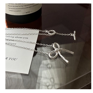Detailed view of silver bow necklace with elegant twist texture and OT toggle clasp closure