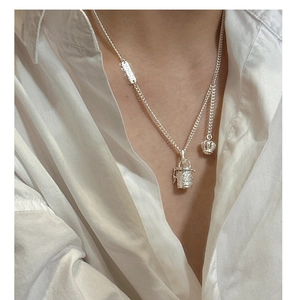 Detail of S925 silver cylinder pendant with crown charm worn on a white shirt