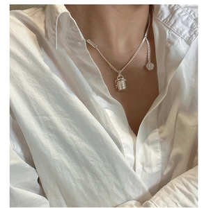 Detail of S925 silver cylinder pendant with scroll pattern on a fine chain worn by a model
