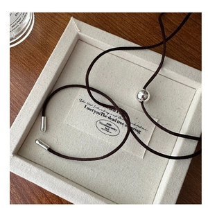 Detail of minimalist dark brown braided cord necklace with silver adjustable metal slider beads
