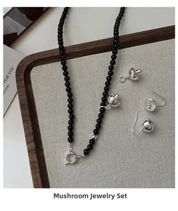 Detail shot of S925 silver mushroom jewelry set with black beads on a wooden display