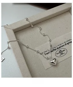 Macro view of S925 sterling silver heart necklace on a textured cream display tray