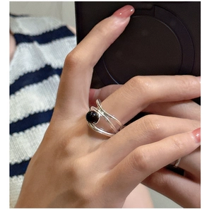 Macro detail of multi-layered silver ring with black onyx stone on striped shirt background