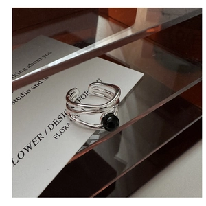 Macro detail of a multilayer S925 silver ring featuring a central black onyx stone bead