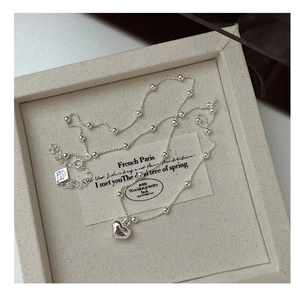 Detail of s925 silver heart pendant necklace with beaded chain on jewelry tray