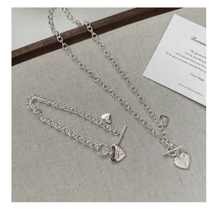 Makroaufnahme von Silber-Herz-OT-Kette und Armband mit eingraviertem Lucky-Schriftzug