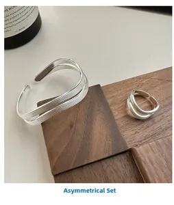 Macro shot of silver plated wave pattern bracelet and ring set on minimalist wooden block