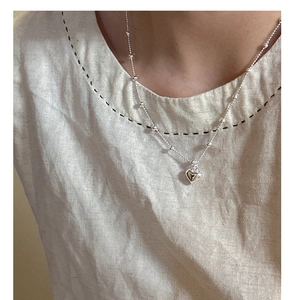 Detailed view of s925 silver heart necklace with beaded chain on a person
