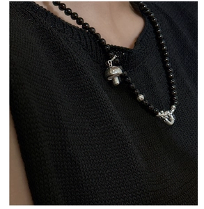 Close-up of a vintage s925 silver mushroom pendant on a black beaded choker necklace
